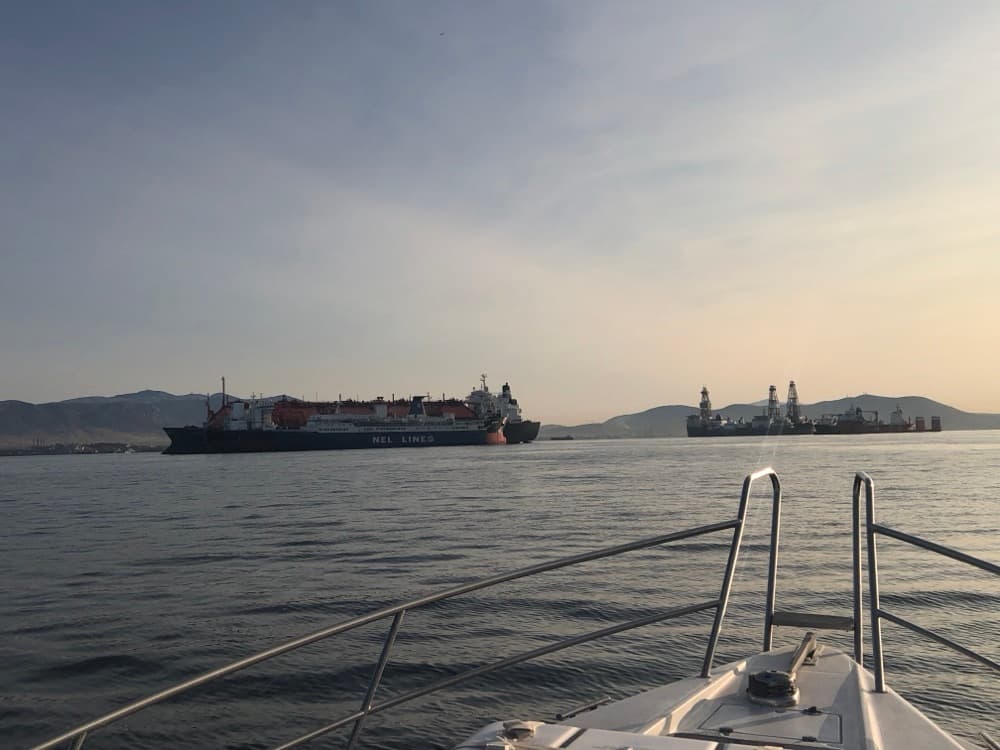 Blick über den Bug auf ankernde Tanker und Frachtschiffe in der Abendstimmung